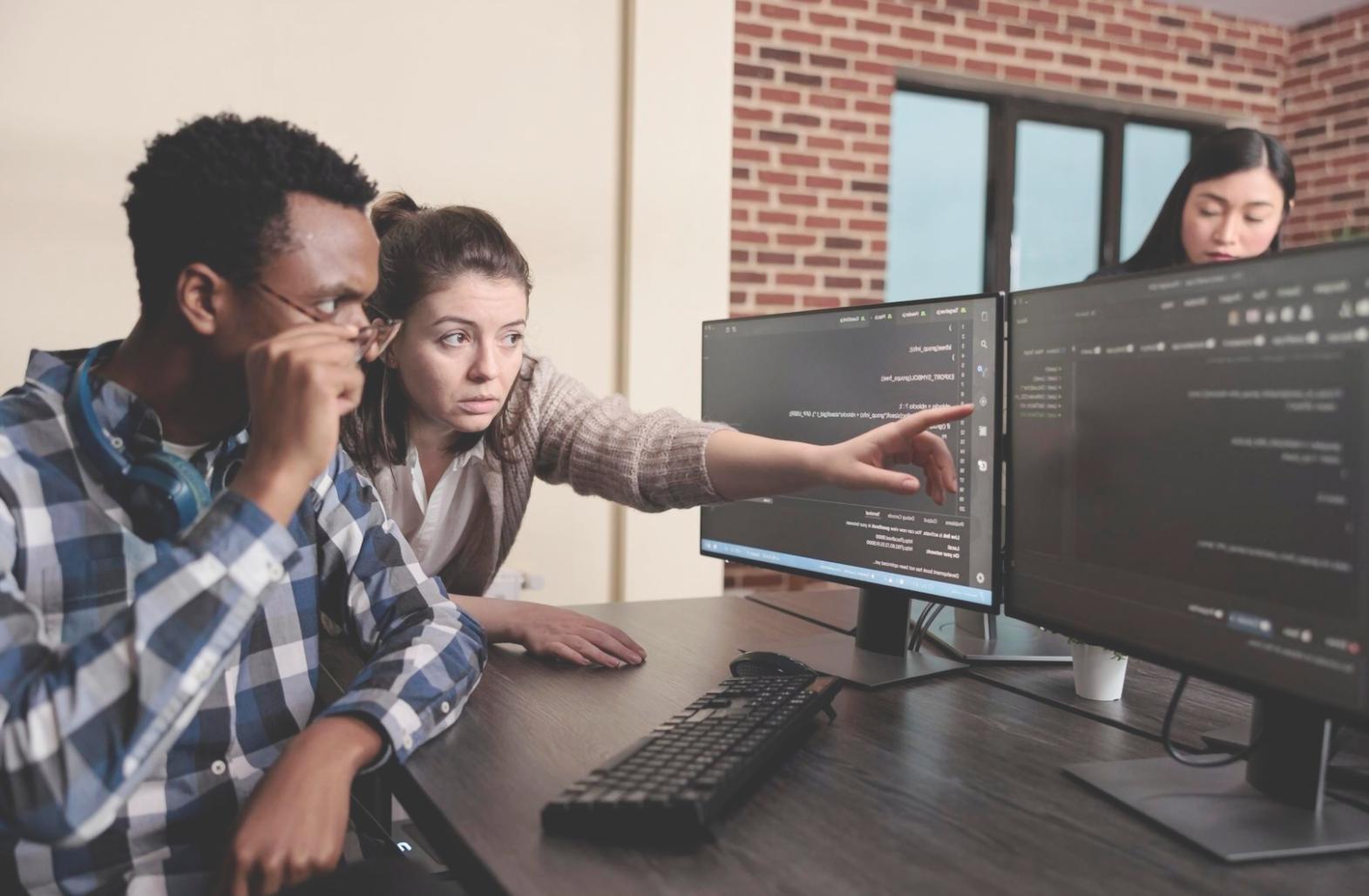 Developer reviewing code analysis results on multiple monitors